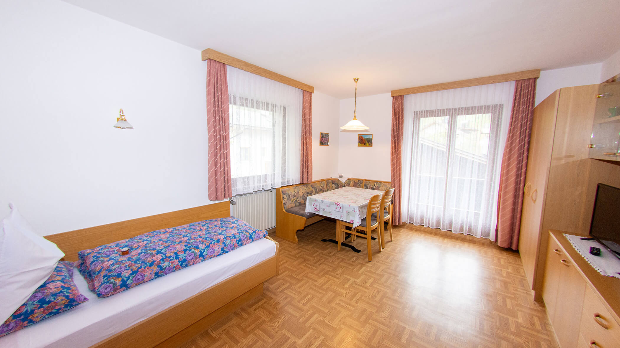 Einzelbett und davor der Esstisch in der Ferienwohnung Alpenrose - Villa Taschler