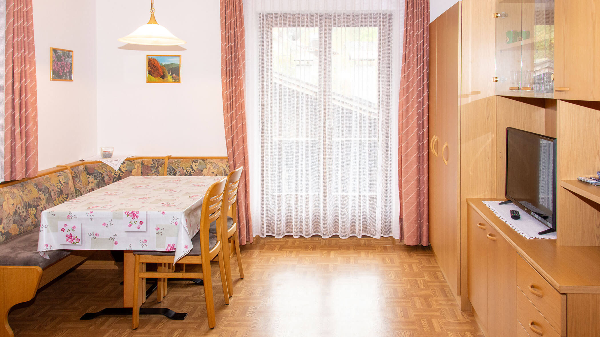 Esstisch mit Ecktisch und Stühlen und daneben eine Fernseherwand in der Ferienwohnung Alpenrose