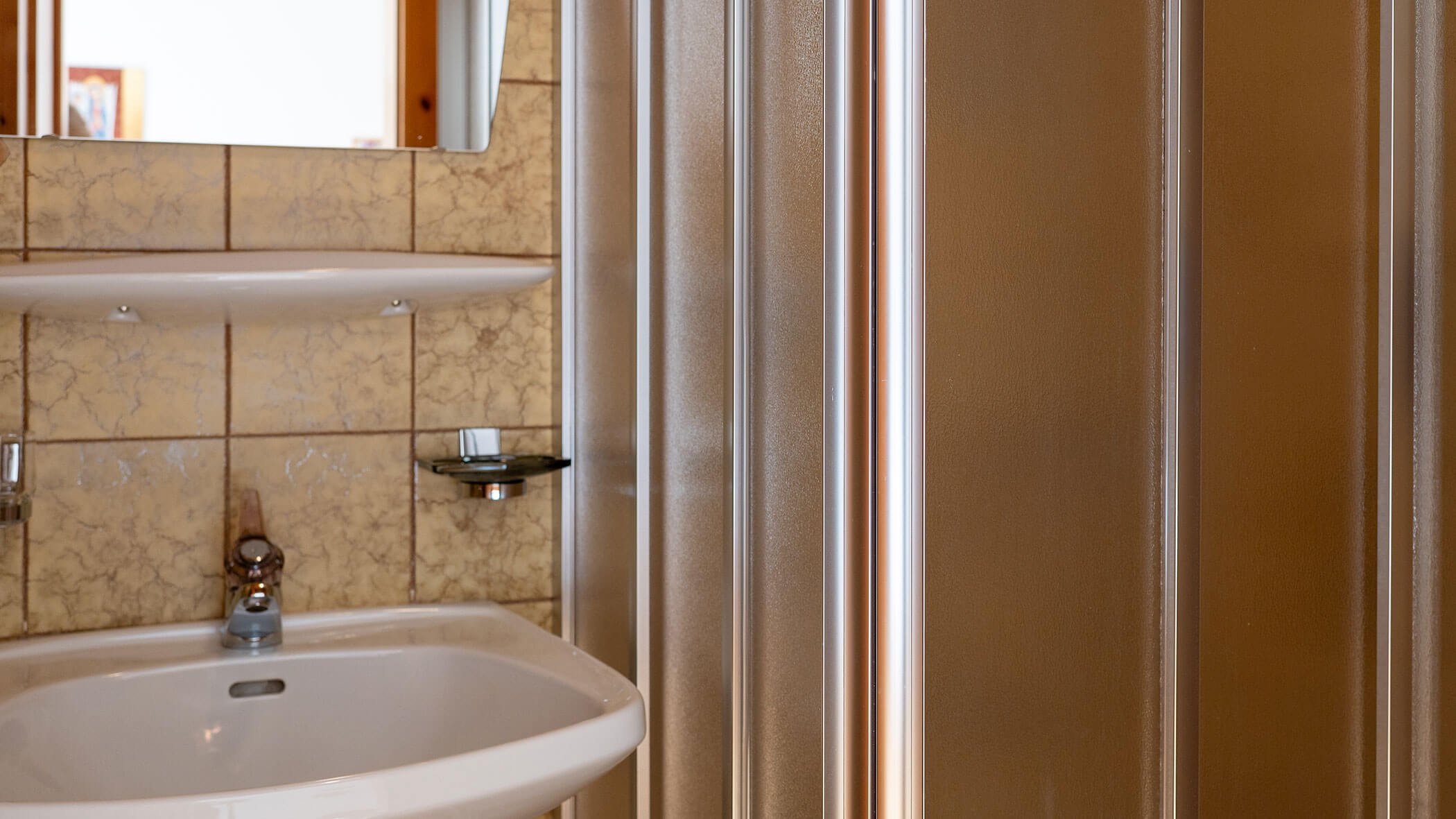 Badezimmer mit Waschbecken und Dusche in der Ferienwohnung Edelweiss - Villa Taschler