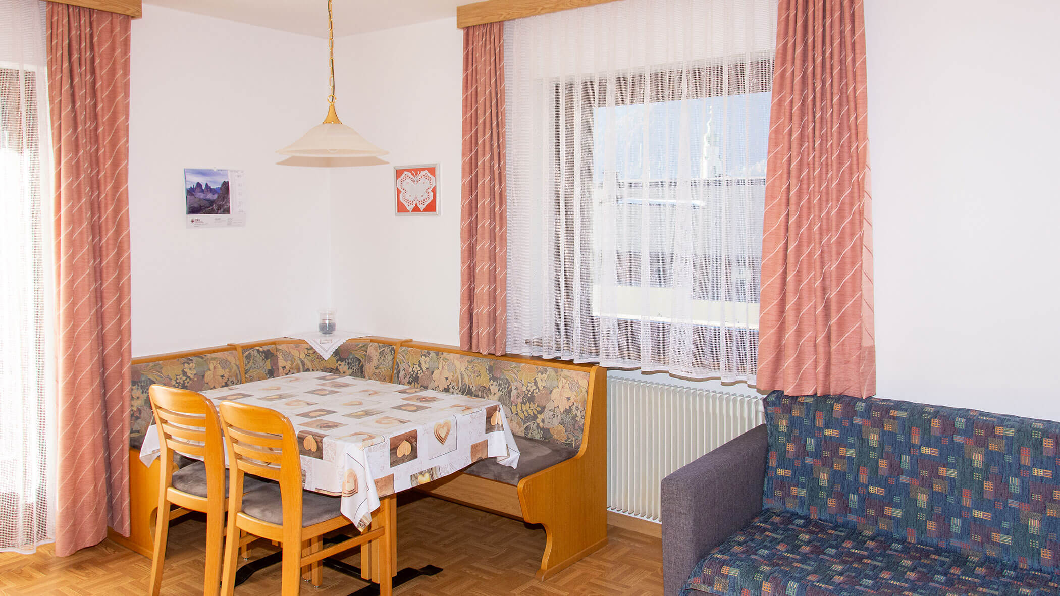 Esstisch mit Eckbank und zwei Stühlen und daneben ein Sofa in der Ferienwohnung Edelweiss - Villa Taschler