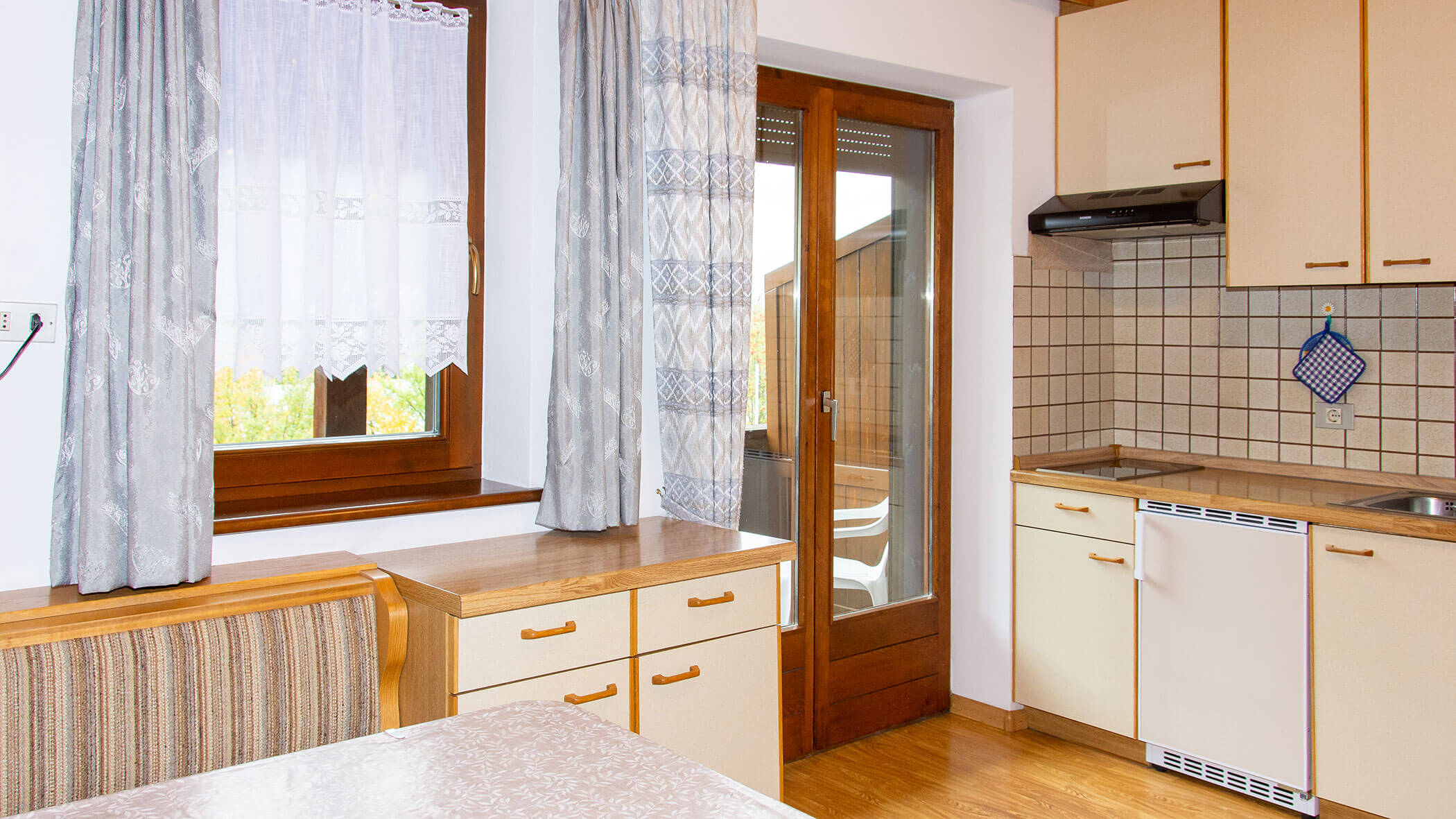 Küche mit Kühlschrank, Herdplatte, Schränken und Esstisch in der Ferienwohnung Pfannhorn - Villa Taschler